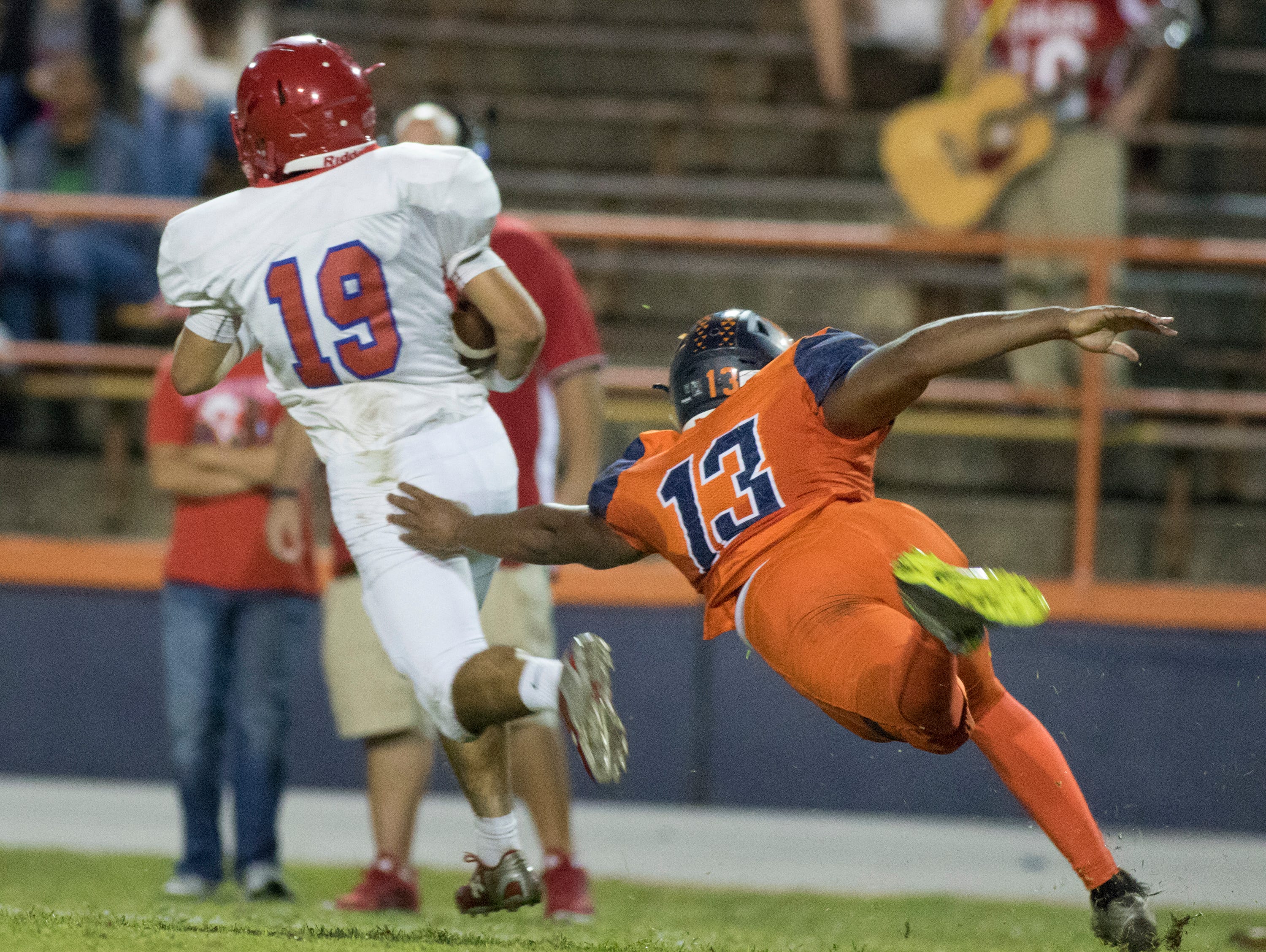 Quaterback Cal West (19) gets past a diving Shontrell Hills (13) during the Pine Forest v Escambia football game on Friday, September 30, 2016.