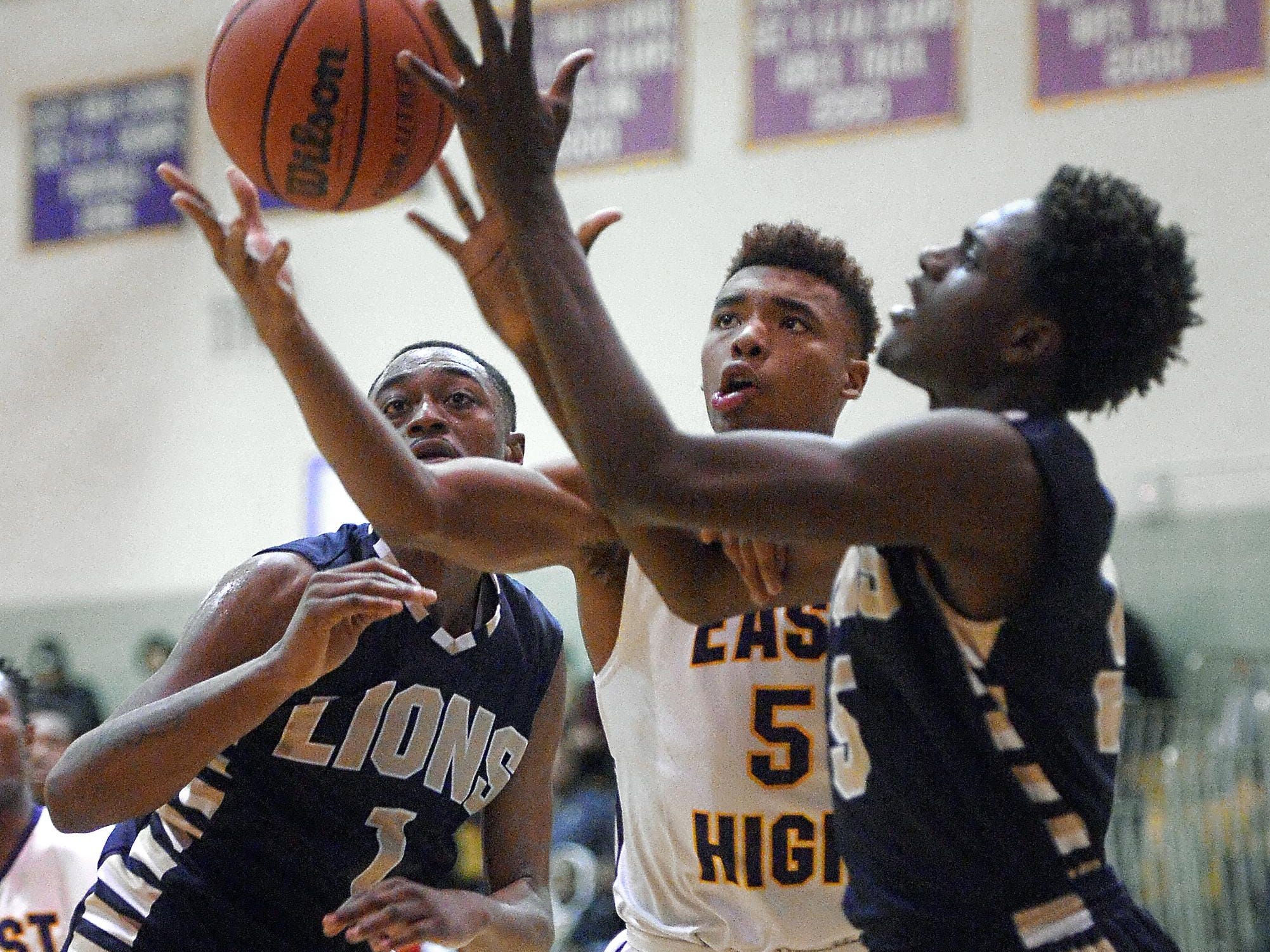East's Theodore Buckner, center, reaches for a rebound between Leadership defenders Tyriek Snow, left, and Tamar Jackson during a RCAC regular season game played at East High School on Tuesday, December 1, 2015.