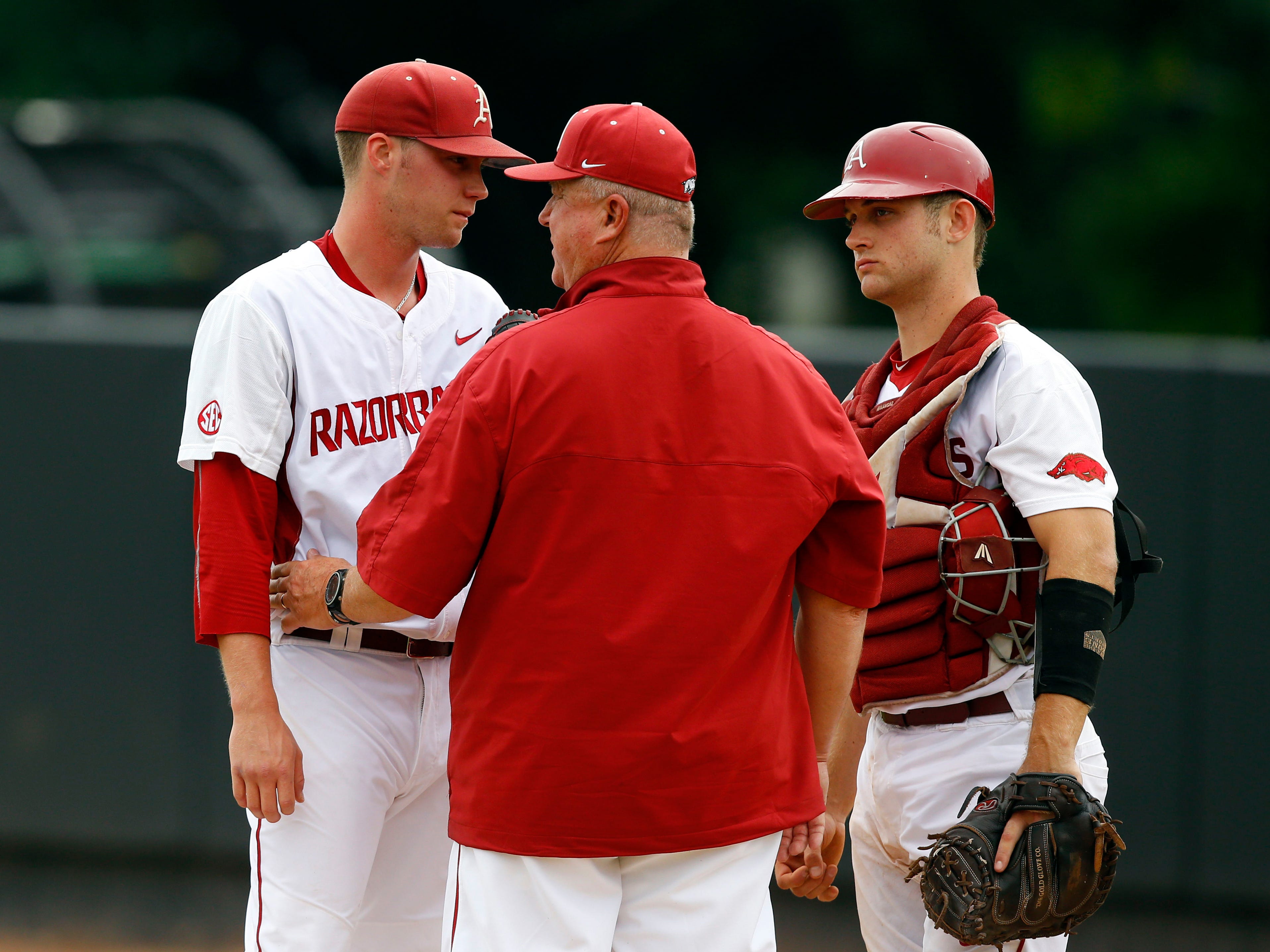 Arkansas pitching coach Dave Jorn, center, talks with starting pitcher Trey Killian and catcher Tucker Pennell in the first inning of a game against Oral Roberts at the Stillwater Regional of the NCAA college baseball tournament in Stillwater, Okla., Friday, May 29, 2015. (AP Photo/Sue Ogrocki)