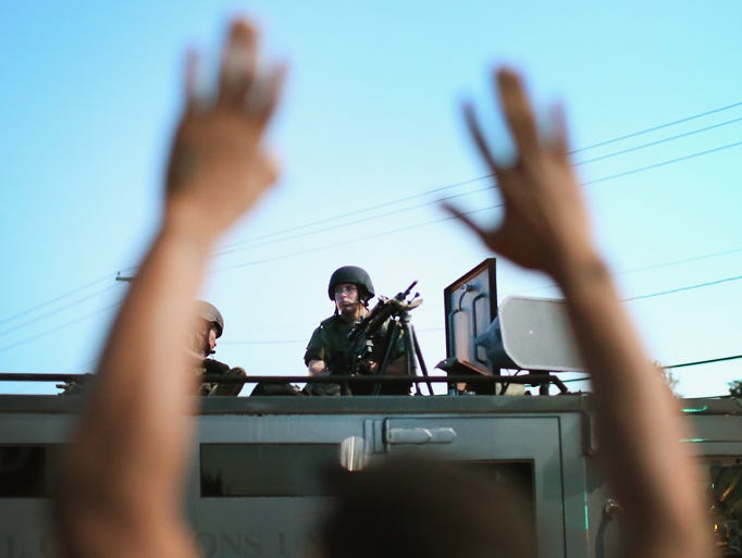 FERGUSON, MO - AUGUST 13: Police stand watch as demonstrators protest the shooting death of teenager Michael Brown on August 13, 2014 in Ferguson, Missouri.