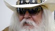 Reporters are reflected in the sunglasses of Leon Russell
