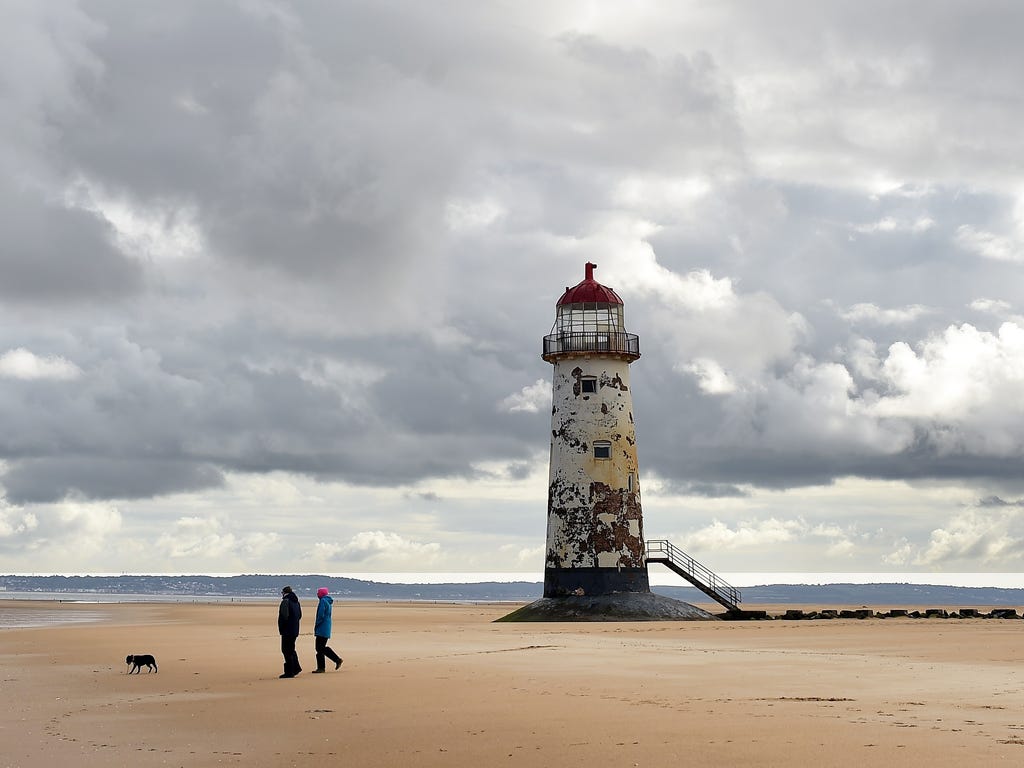 People walk as they cross the beach near the Point of Ayr Lighthouse in Talacre in north Wales.