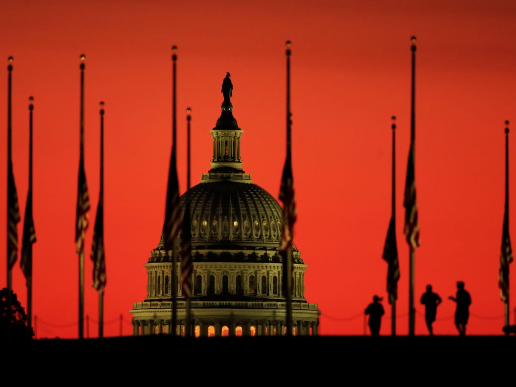 The U.S. Capitol dome backdrops flags at half-staff in honor of the victims killed in the Las Vegas shooting as the sun rises on Oct. 3, 2017, at the foot of the Washington Monument on the National Mall in Washington.