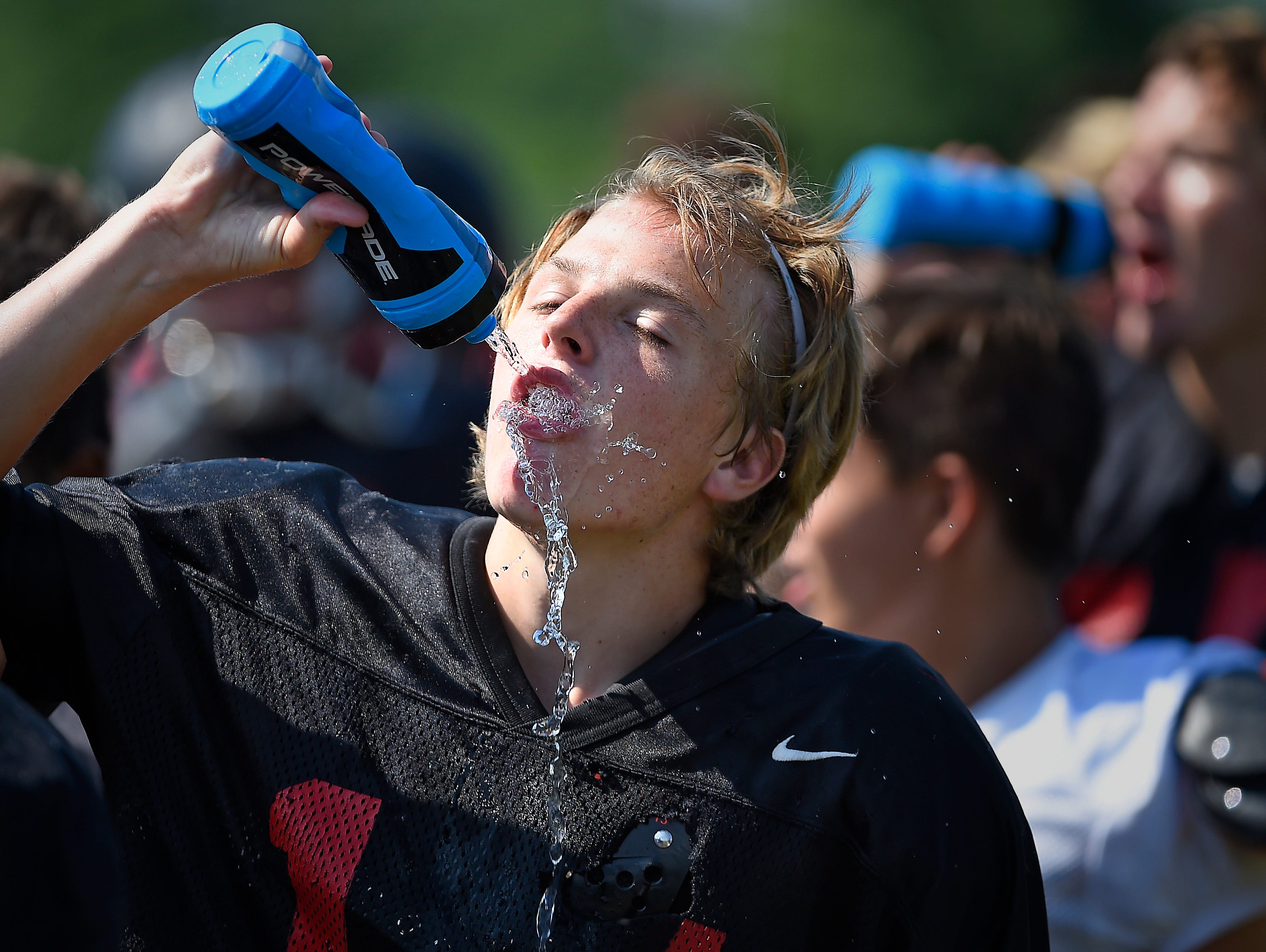 Nick Stallcup stays hydrated to beat the heat Monday during a brief break in practice. Ravenwood joined with other high school football teams across the Midstate on the first day of practice in full pads.