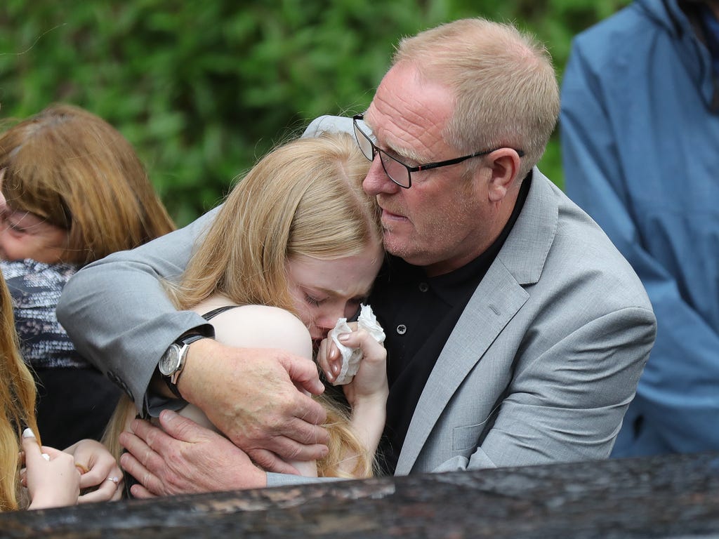 Steve Howe, the husband of Manchester attack victim Alison Howe, embraces family members as Alison's funeral cortege leaves St. Anne's Church in Oldham, England. Alison Howe was among 22 people who died in the suicide bombing at Manchester Arena as s