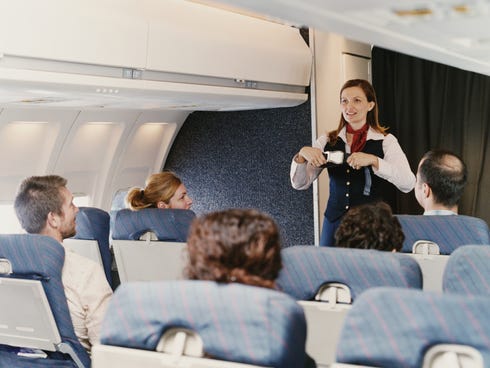 A flight attendant demonstrates safety procedures to passengers on a plane.