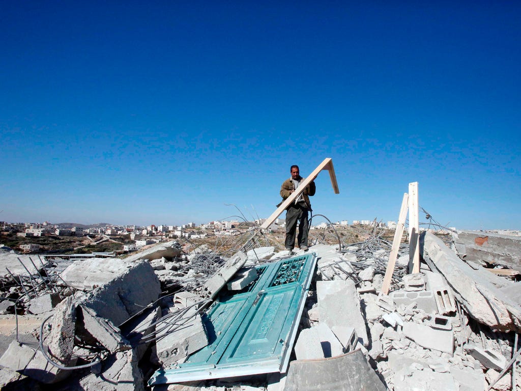 A Palestinian man helps clear the debris of a home after it was demolished, by Israeli bulldozers bulldozers as they were reportedly built illegally without a permit, near the West Bank town of Hebron on March 6, 2017.