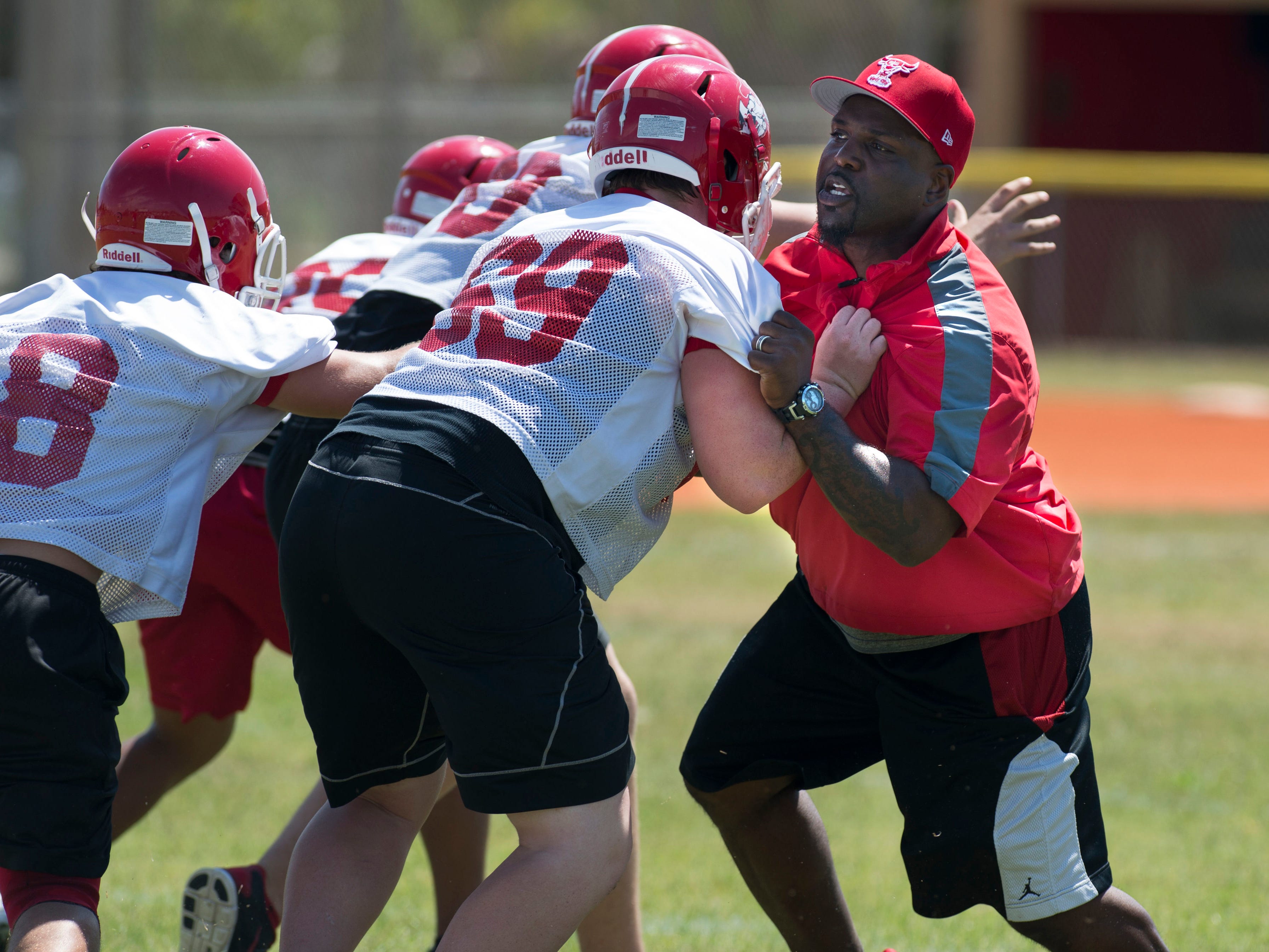North Fort Myers High School football head coach Earnest Graham, right, gets involved first hand in the team's first practice, Monday at the school's practice field. The former University of Florida Gators and Tampa Bay Buccaneers running back takes on the challenge of rebuilding the Red Knights football program.