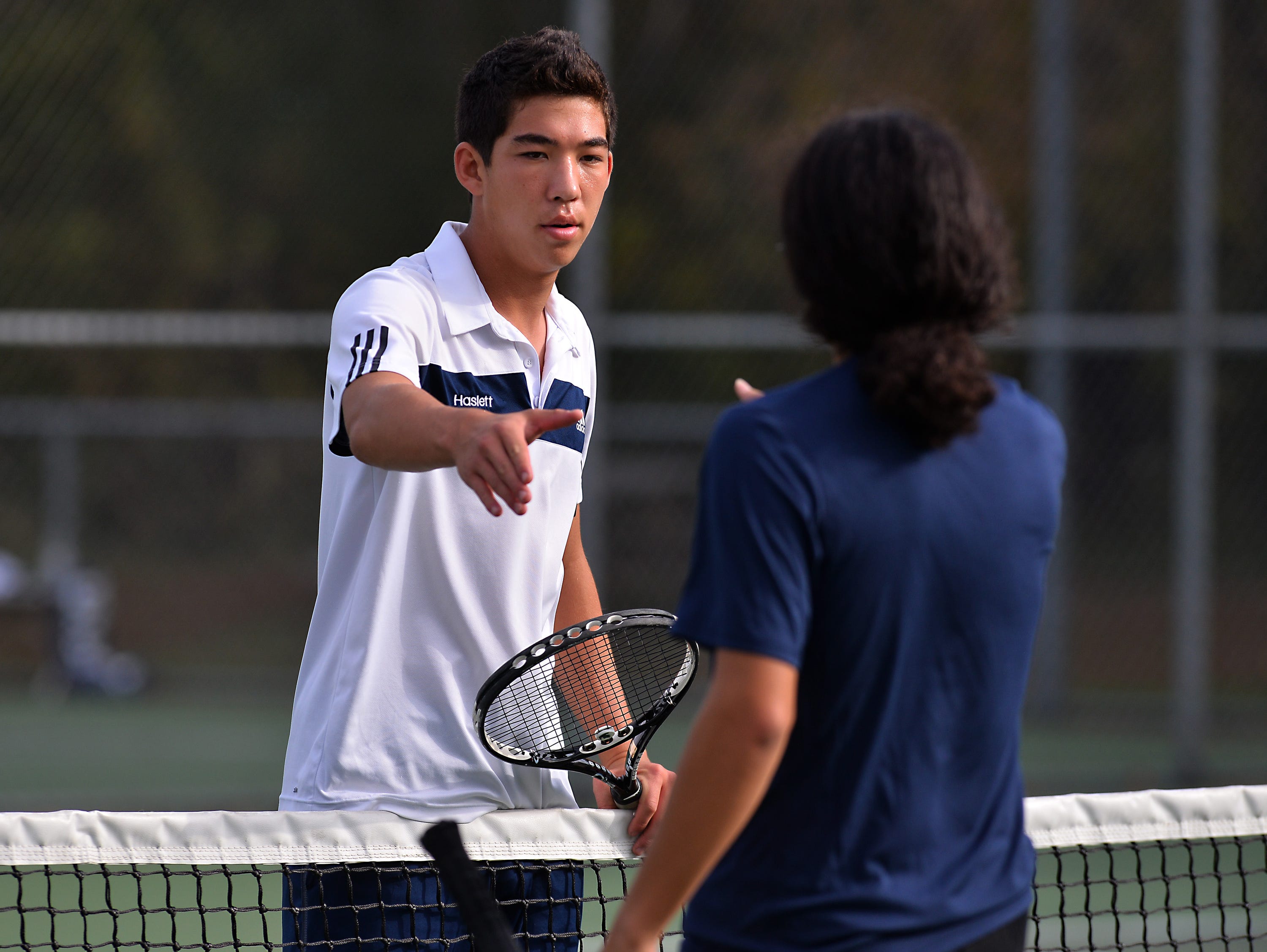 Haslett's Nate Choi left, and Eastern's Jonathan Hudy-Velasco, right, shake hands at the net Thursday 10/8/2015 after Choi won their match in early action of tennis regionals.