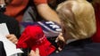 Trump signs a hat after speaking at a rally at the