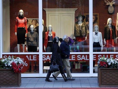 Shoppers walk in front of a store advertising a sale on Dec. 9, 2013, in San Jose.