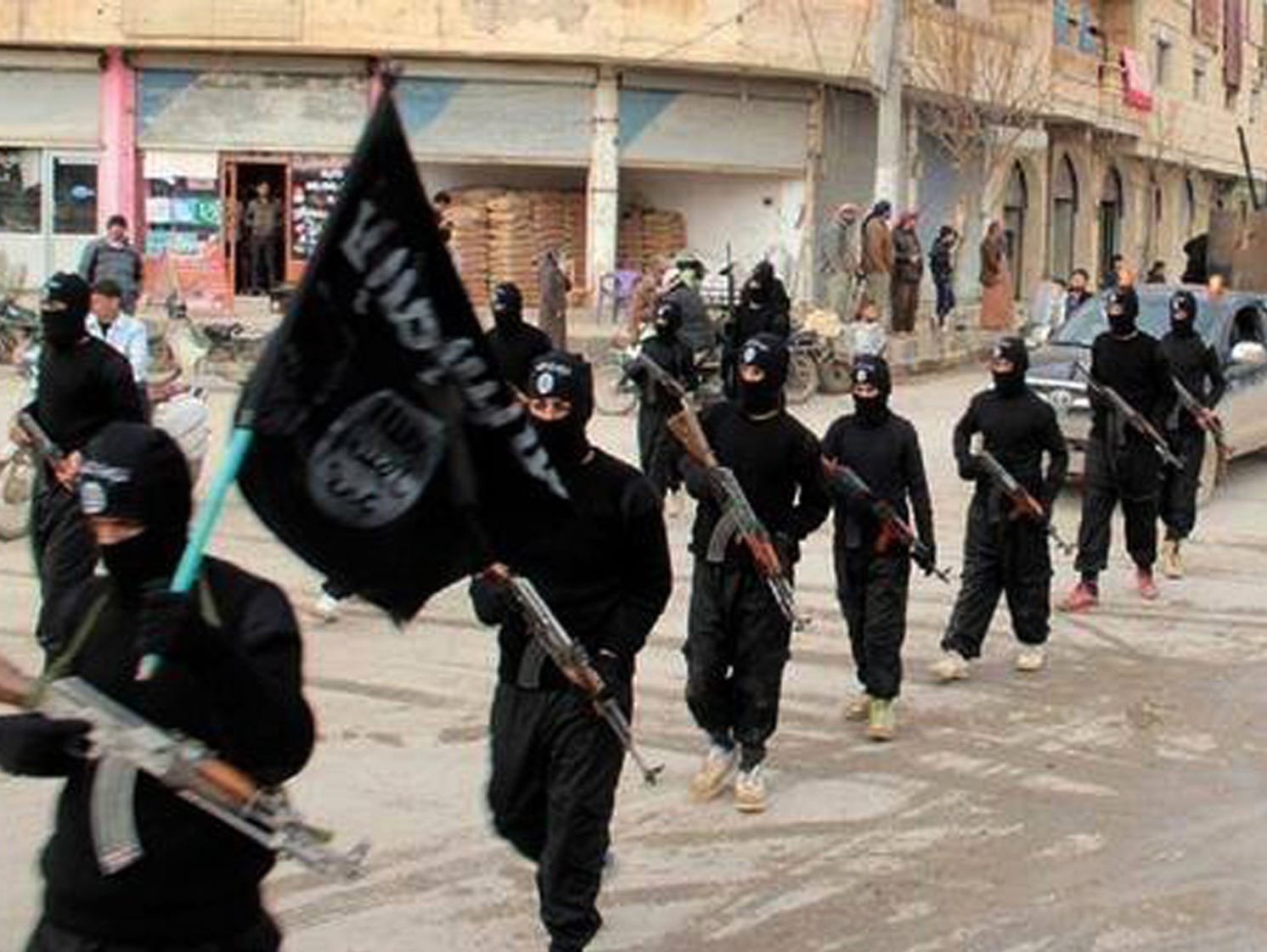 This undated file image posted on an extremist website on Jan. 14, 2014, shows fighters from the Islamic State group marching in Raqqa, Syria.