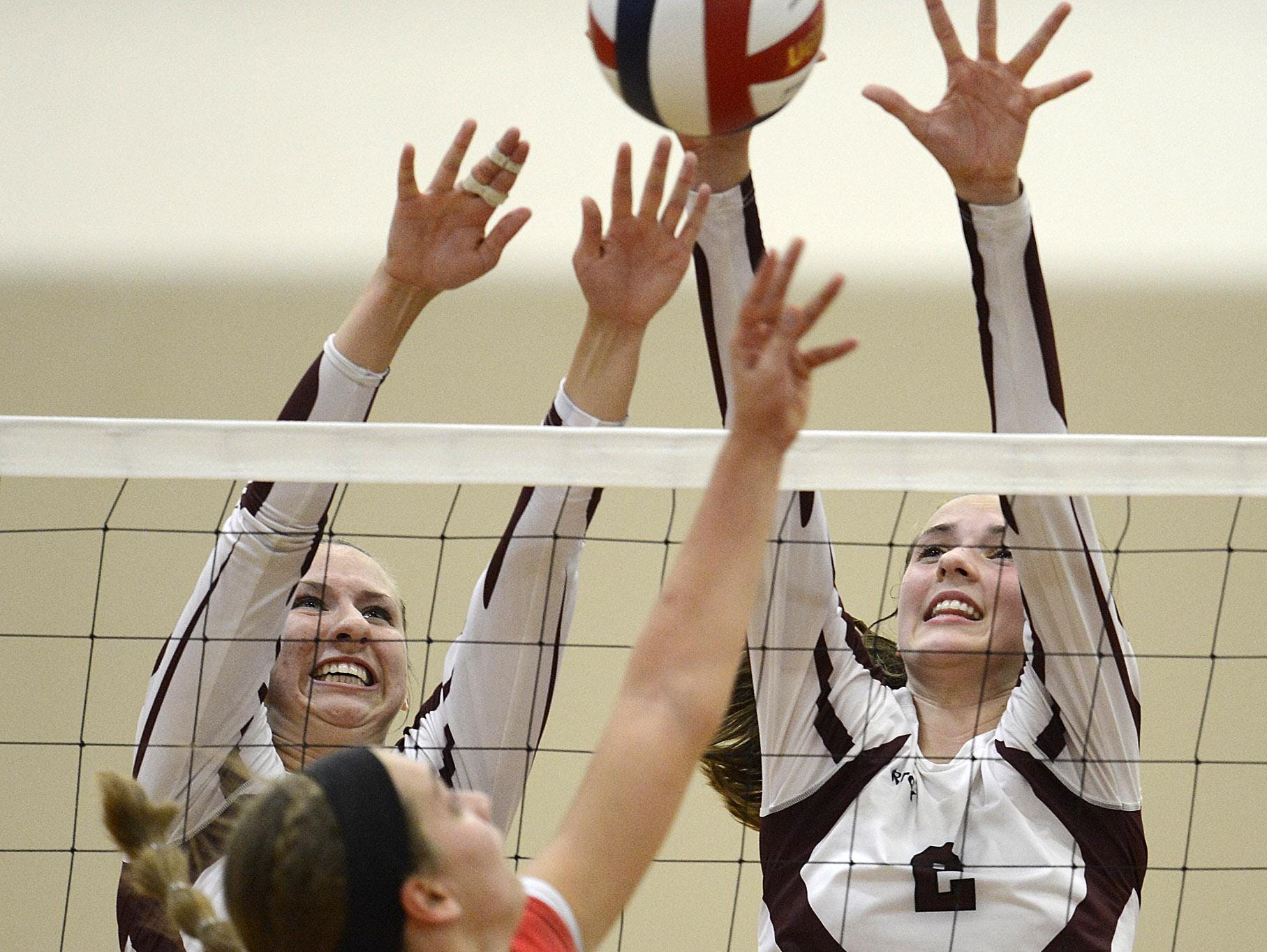 De Pere’s Lindsey Mirkes (2) and Ashley Smits (4) team up to block a shot attempt by Manitowoc’s Cassidy Mrotek (9) during Thursday night’ volleyball match at De Pere.