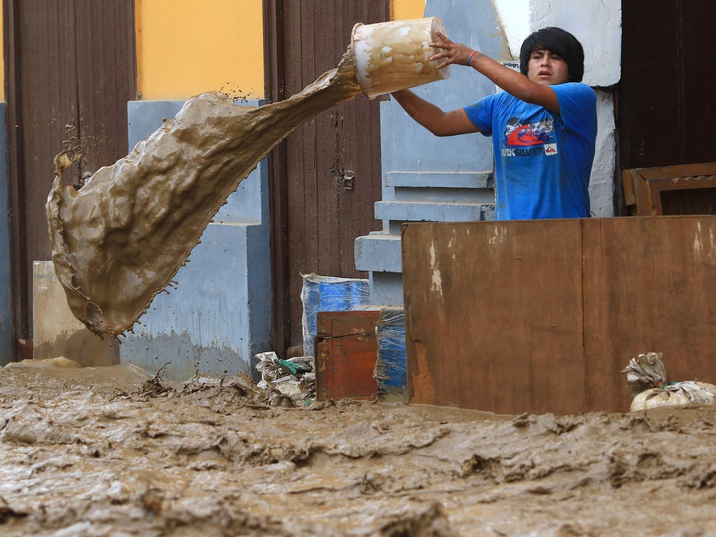 A local resident bails water from behind a barrier as a flash flood hits the city of Trujillo, 354 miles north of Lima on March 18, 2017, bringing mud and debris.\u000aThe El Nino climate phenomenon is causing muddy rivers to overflow along the entir