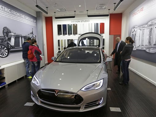 Customers check out a new Tesla all electric car, Monday,