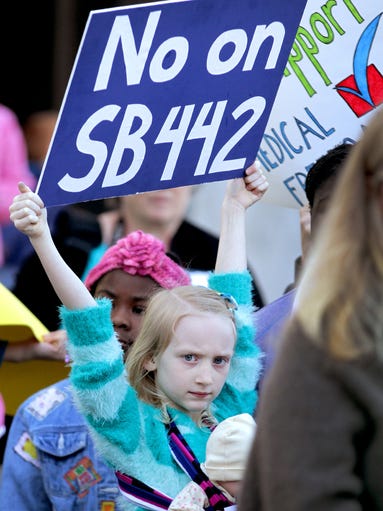 Jewel McCullough, 6, of McMinnville, carries a sign