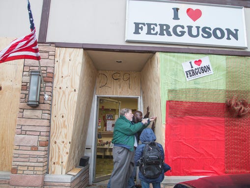 Paul Morris (center front) boards up his store in Ferguson