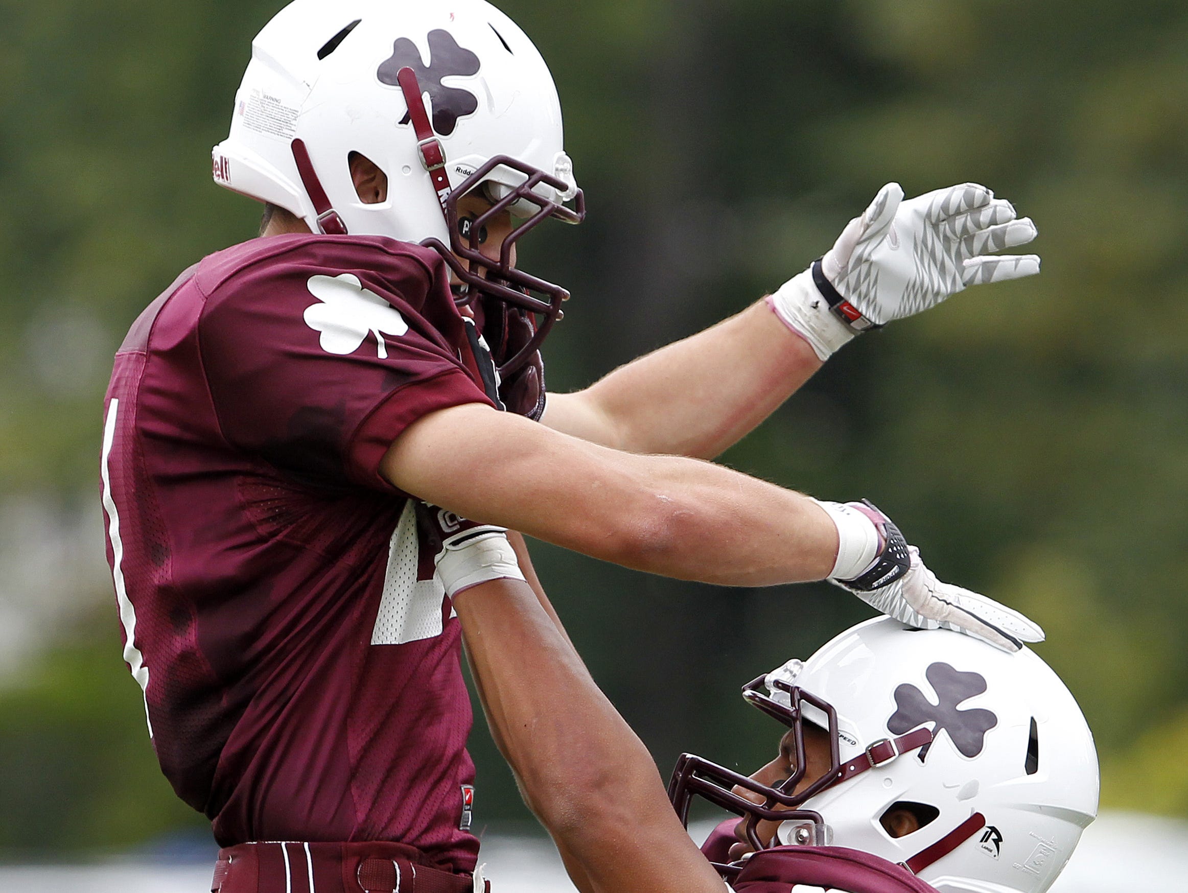 In this file photo, Aquinas' Mike Messina, left, is hoisted into the air by teammate Chris Bostick after a touchdown during a 2010 regular season game versus McQuaid.