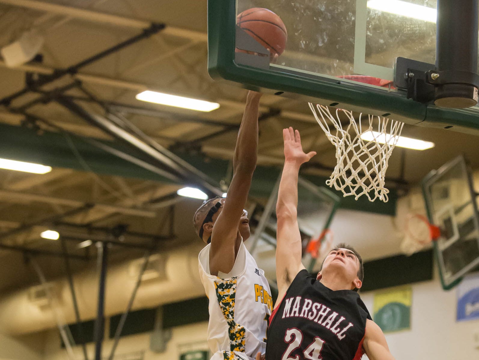 Marshall's Drew DeVine (24) defends as Pennfield's Francois Jamierson (11) goes for the hoop during Friday night's game.