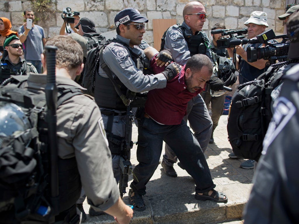 Israeli police officers detain a Palestinian man outside the Lion's Gate, following an appeal from clerics to pray in the streets instead of the Al Aqsa Mosque compound, in Jerusalem's Old City on July 19, 2017. A dispute over metal detectors has esc