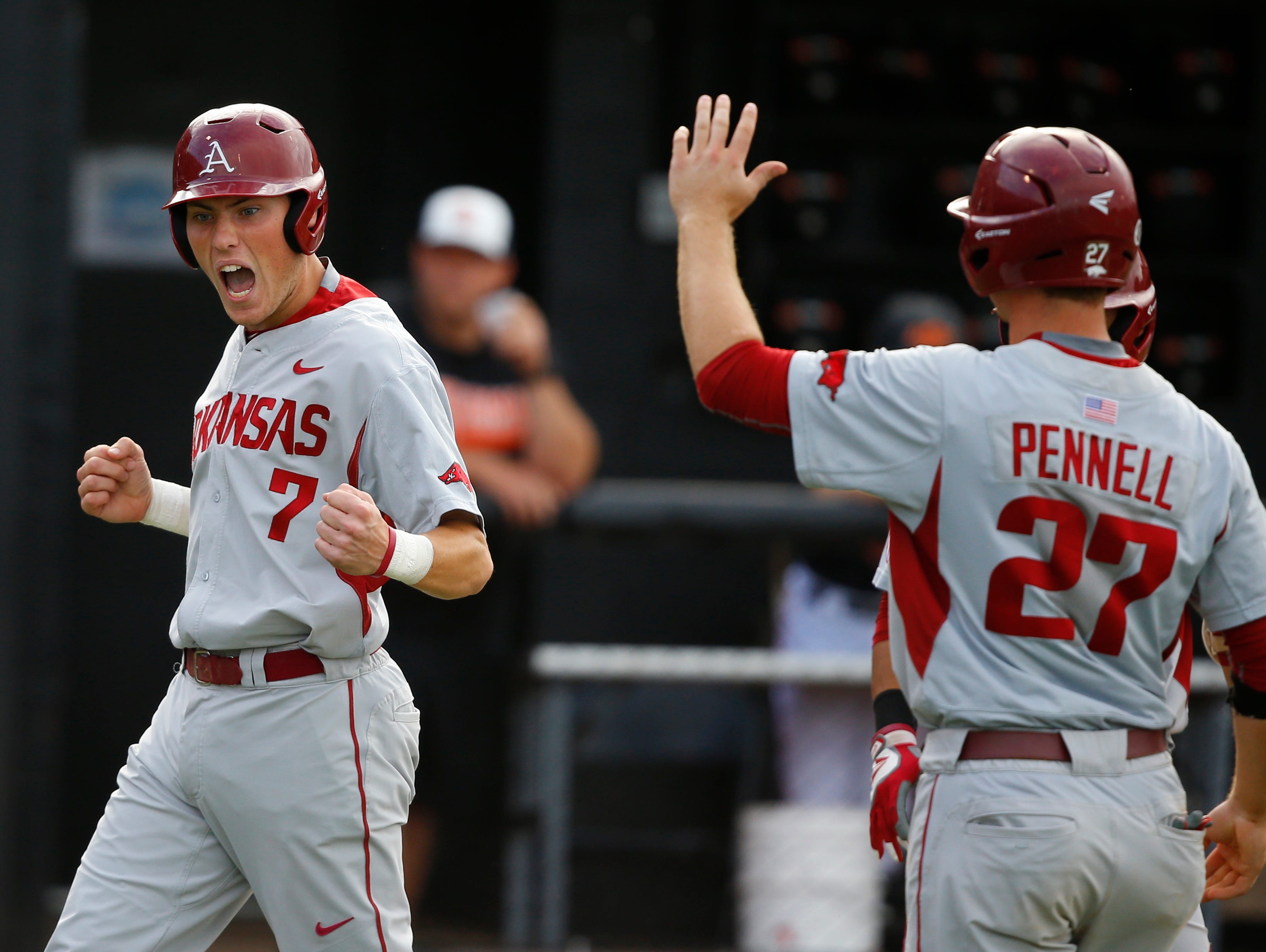 Arkansas' Bobby Wernes (7) and Tucker Pennell (27) celebrate after Wernes scored on a hit by Tyler Spoon in the third inning against Oklahoma State during action at the Stillwater Regional on Saturday night. The Razorbacks rallied for a 7-5 win.
