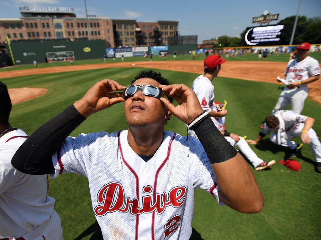 The Greenville Drive player Santiago Espinal watches the solar eclipse when the game was stopped at Fluor Field in Greenville, S.C.