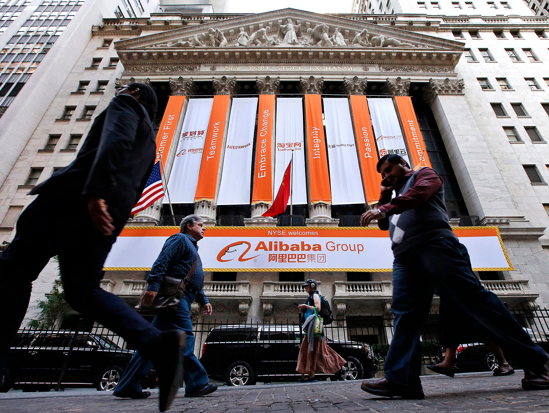Pedestrians pass by the New York Stock Exchange on the day of Alibaba's initial public offering, Sept. 19, in New York.