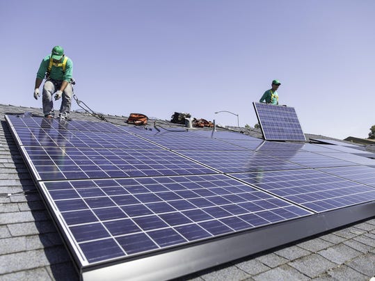 File photo: Workers install solar panels on the roof of a home. (Photo 