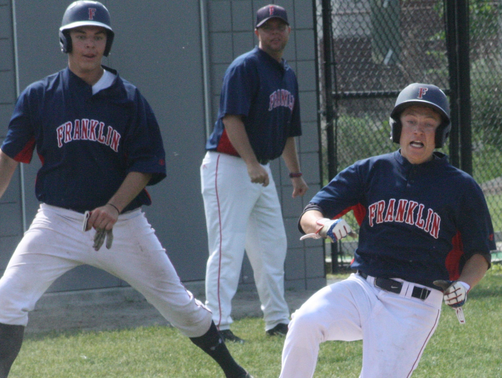 Franklin's Tyler Camp slides home with the Patriots' second run as Ryan Prohaska and head coach Matt Fournier look on.