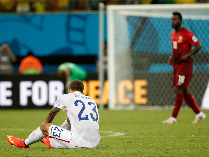 United States defender Fabian Johnson sits on the ground after the final whistle as Portugal forward Varela, who scored the tying goal, walks past.