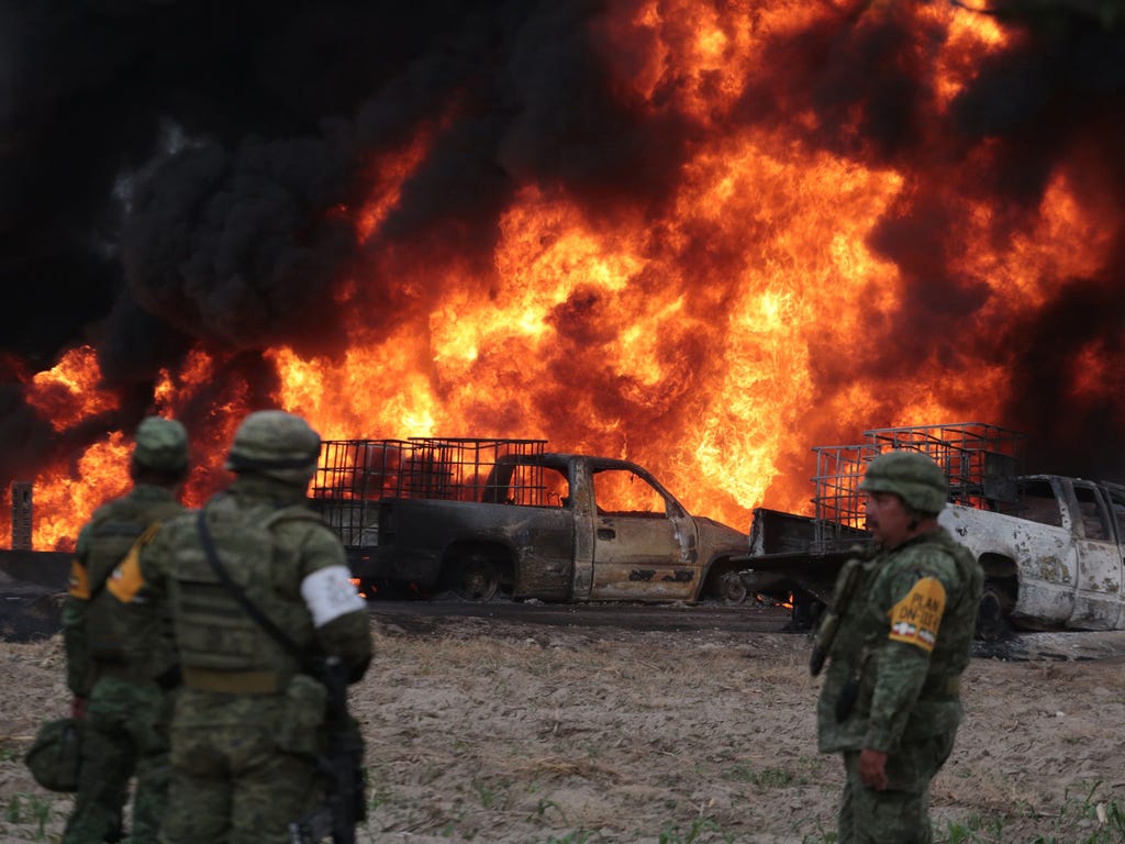 Mexican army soldiers stand in front of the flames generated by a fire in a clandestine fuel valve in Santa María Nenetzintla, Amozoc, Puebla, on May 7, 2017. The theft of fuel has put the war in several states of central Mexico, with violent 