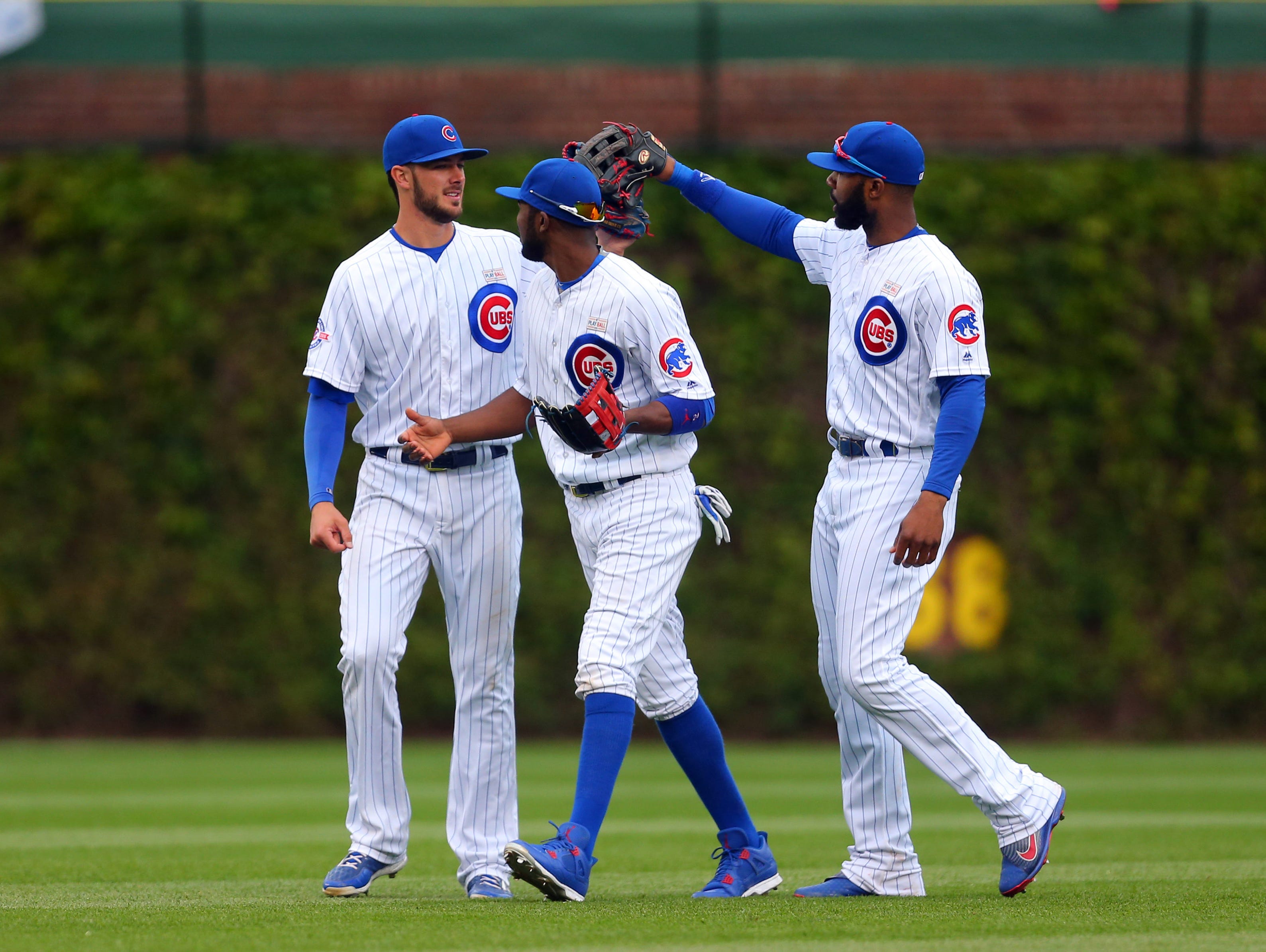 Cubs left fielder Kris Bryant (left) and center fielder Dexter Fowler (right) and right fielder Jason Heyward (right) celebrate the final out.