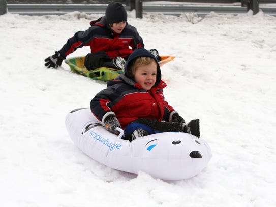 Children sled on the snow-covered hill behind East
