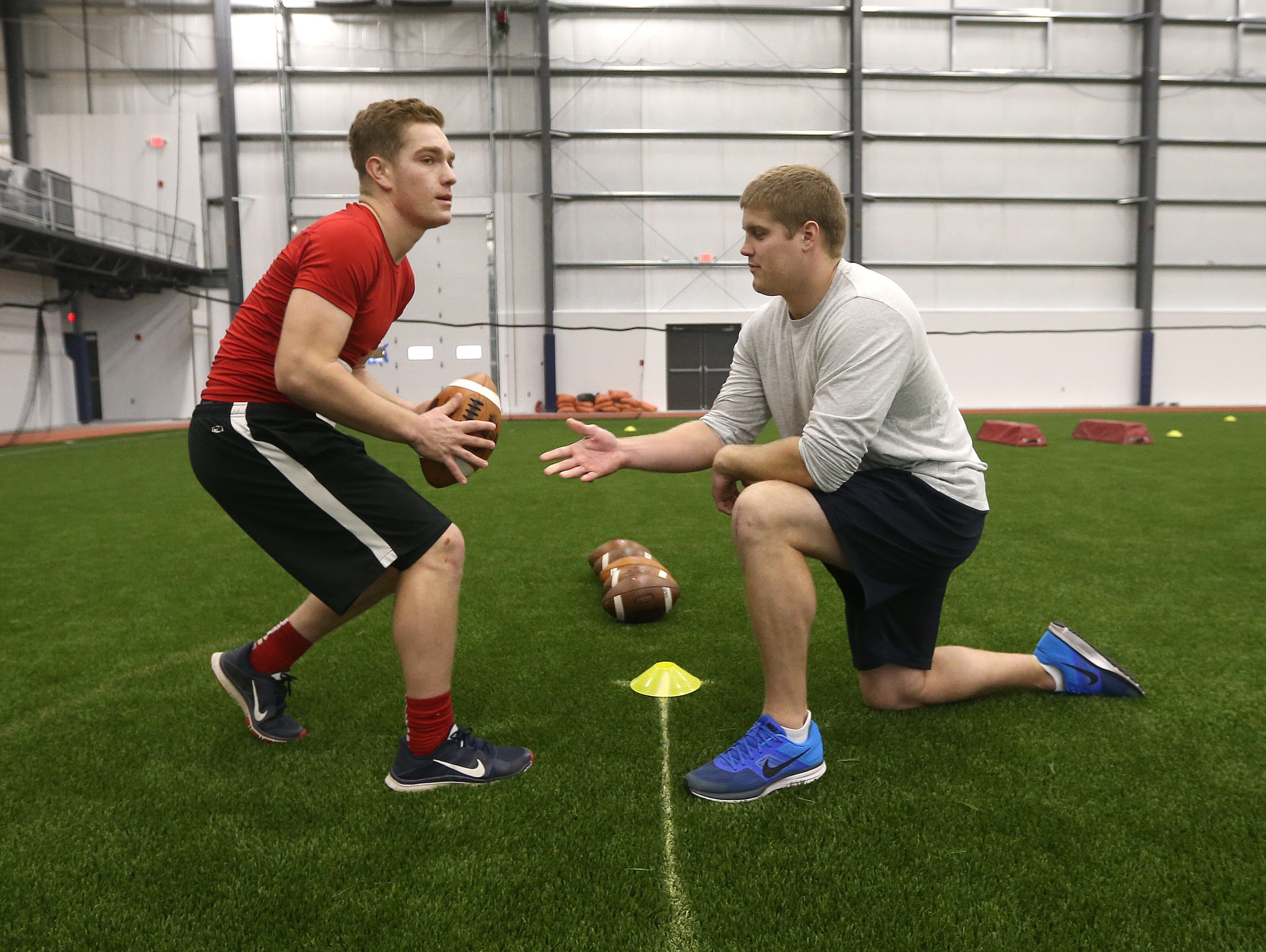 Former NFL player Chris White snaps the ball to Hilton quarterback Johnathan Letta during drills at the AGR Sports Combine at Pinnacle Athletic Campus in Victor.