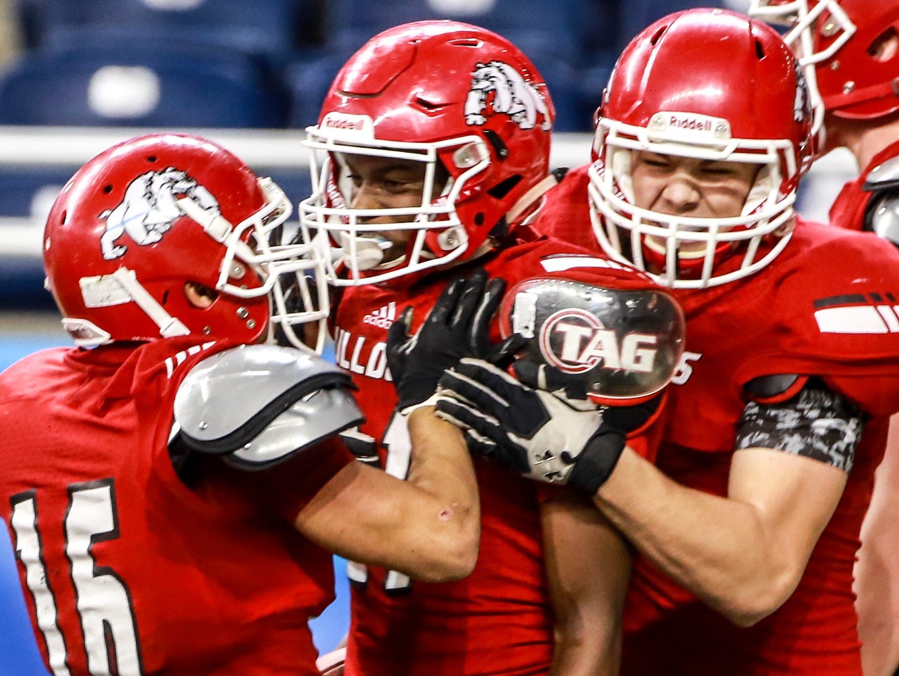 Romeo WR Bradley Tanner, center, celebrates scoring a touchdown with his teammates, Hunberto Flores and Louis Thom, during the first half Michigan High School Athletic Association football Division 1 finals against Detroit Cass Tech at Ford Field in Detroit on Saturday, Nov. 28, 2015.