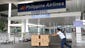 A delivery man passes a Philippine Airlines sign at the domestic flights entrance at the international airport in Manila.  Hundreds of flights have been cancelled due to Typhoon Haiyan.