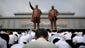 North Koreans bow in front of bronze statues of the