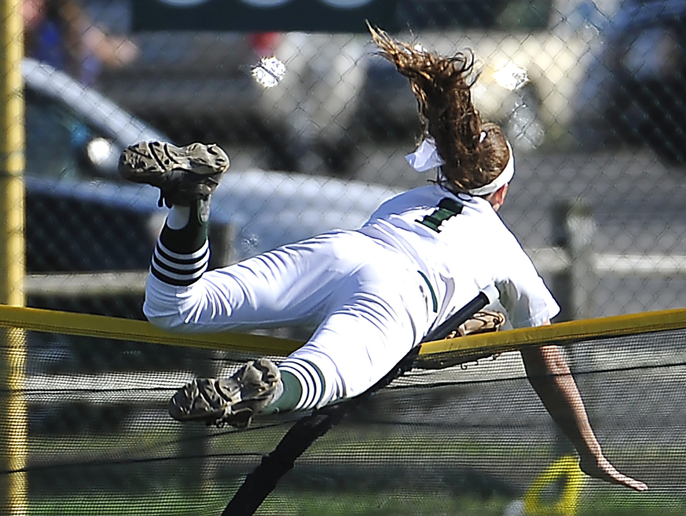 Outfielder Brooke Eakes goes over the fence after catching what would have been a home run as Friendship Christian plays Kings Academy in the A championship game Friday.