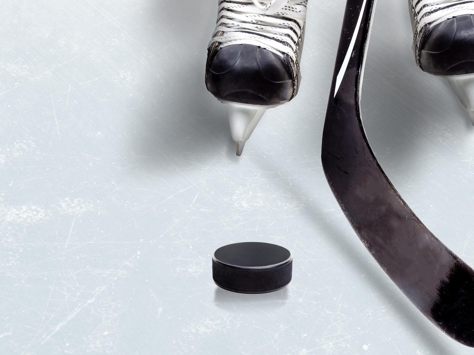 Ice hockey game showing stick on puck with part of player's skates on ice and copy space.