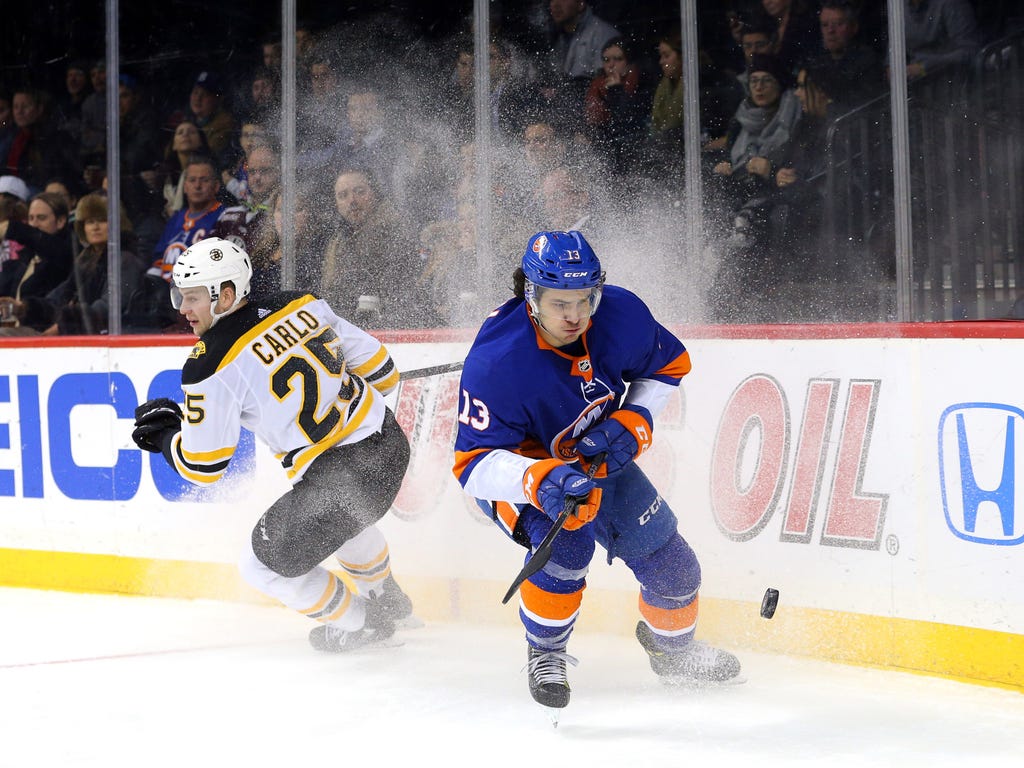 New York Islanders center Mathew Barzal, right, plays the puck against Boston Bruins defenseman Brandon Carlo during the second period at Barclays Center.
