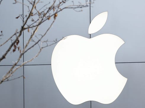 A woman walks past the Apple logo at an Apple Store building in China.