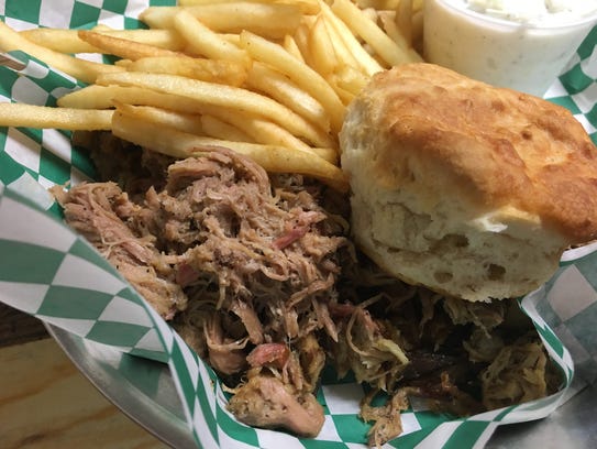 A pulled pork plate with coleslaw, fries and a biscuit