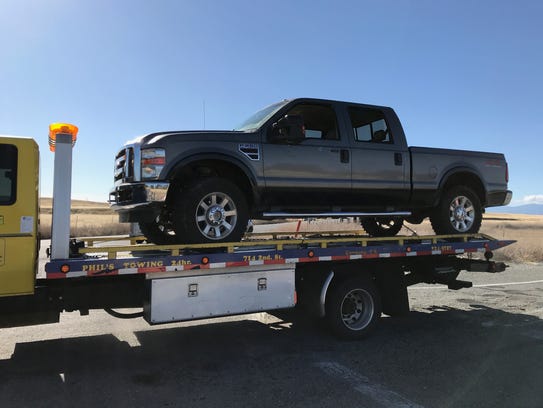 A tow truck removes a pickup with bullet holes in its