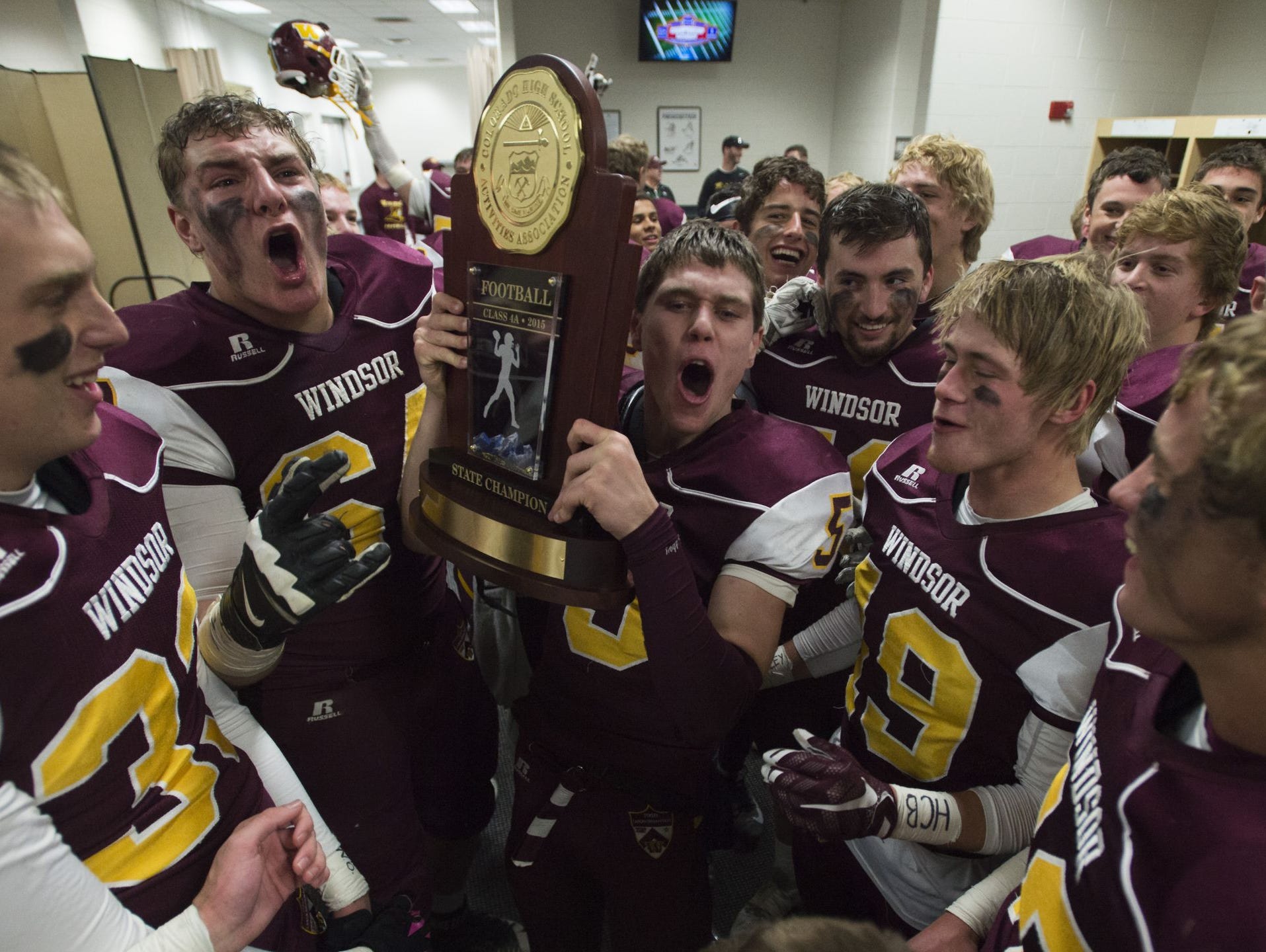 The Windsor High School football team celebrates with the Class 4A trophy at Sports Authority Field at Mile High.