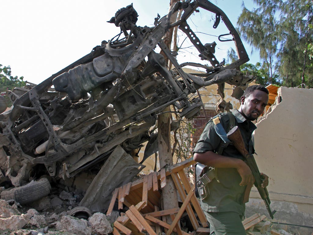 A Somali soldier stands near the wreckage from a car bomb blast and gun battle targeting a restaurant in Mogadishu, Somalia on June 15, 2017. Somalia's security forces early Thursday morning ended a night-long siege by al-Shabab Islamic extremists at