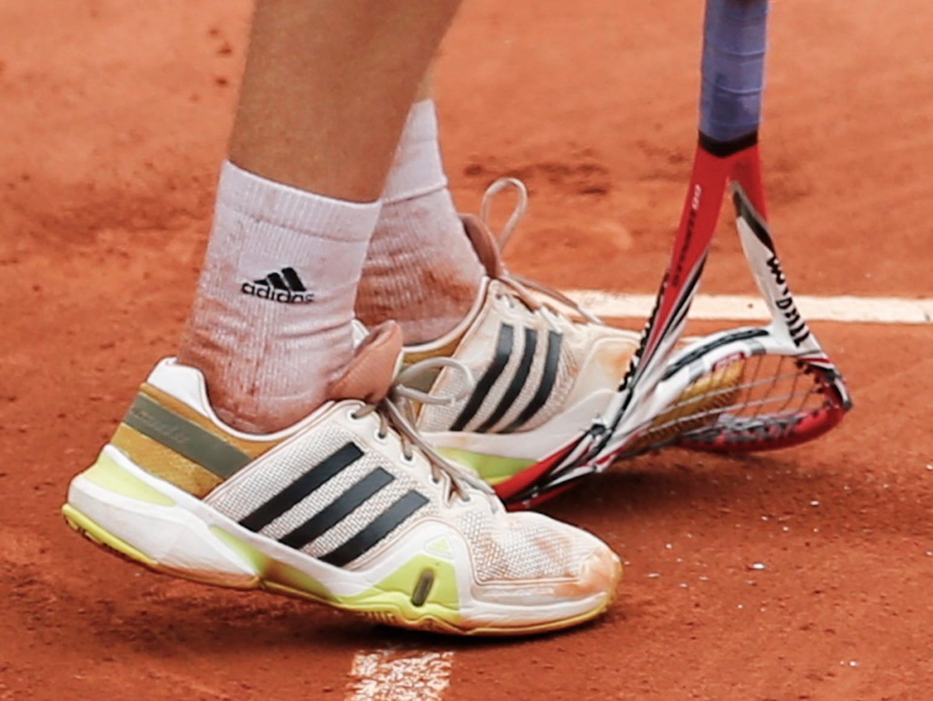 Ernests Gulbis of Latvia steps on his racket during his men's singles match against Roger Federer of Switzerland.