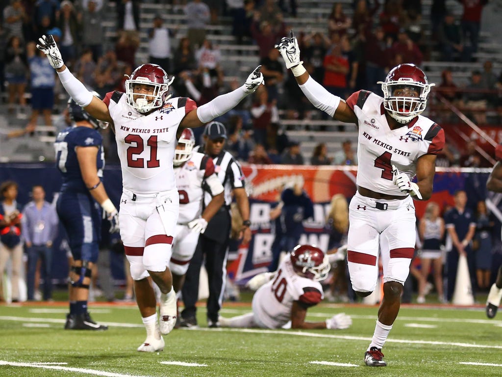 DeMarcus Owens (4), Jaden Wright (21) and New Mexico State celebrate after clinching victory over Utah State at the Arizona Bowl in Tucson. New Mexico State prevailed 26-20 in overtime for its first bowl win since 1960.