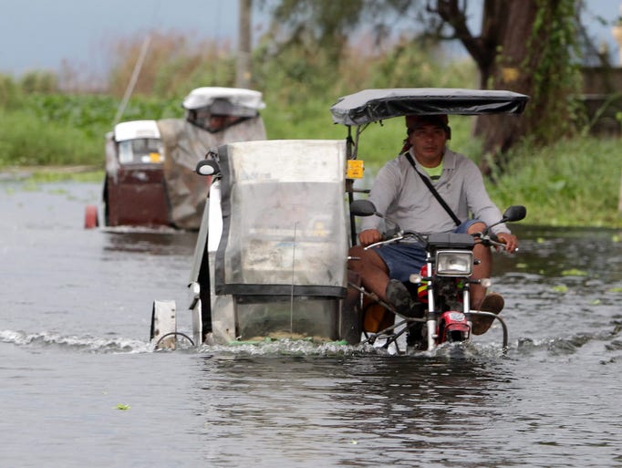 Filipinos riding on three wheeled motorcycles maneuver through floodwaters in Taguig city, south of Manila, Philippines on Nov. 8 after Typhoon Haiyan swept through the area.
