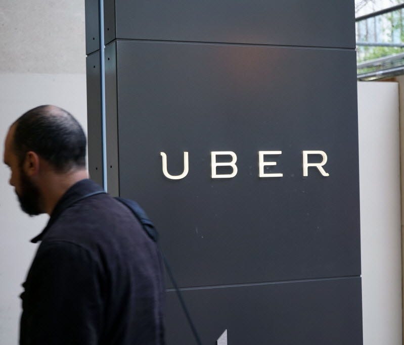 A man walks past the sign for the Uber headquarters in downtown San Francisco.