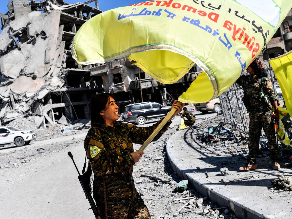 Rojda Felat, a Syrian Democratic Forces (SDF) commander, waves her group's flag at the iconic Al-Naim square in Raqa on Oct. 17, 2017.\u000aU.S.-backed forces said they had taken full control of Raqa from the Islamic State group, defeating the last j